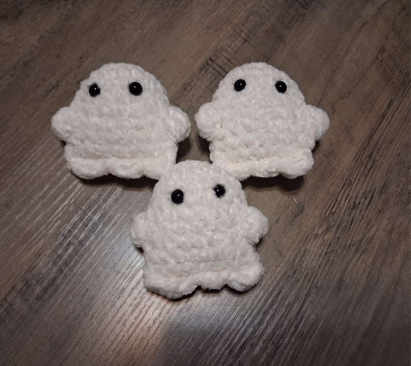 Three plush white crocheted pocket ghosts with black bead eyes
