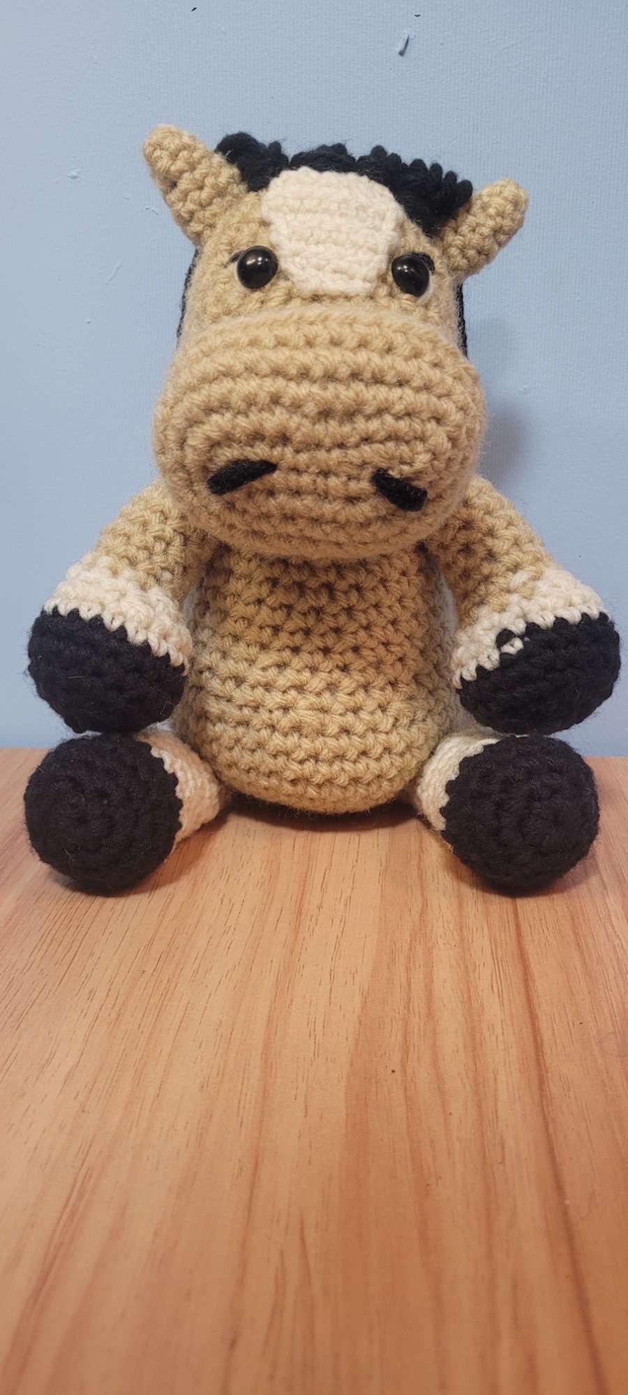 Tan crocheted horse plush with a black mane, white blaze, and black hooves